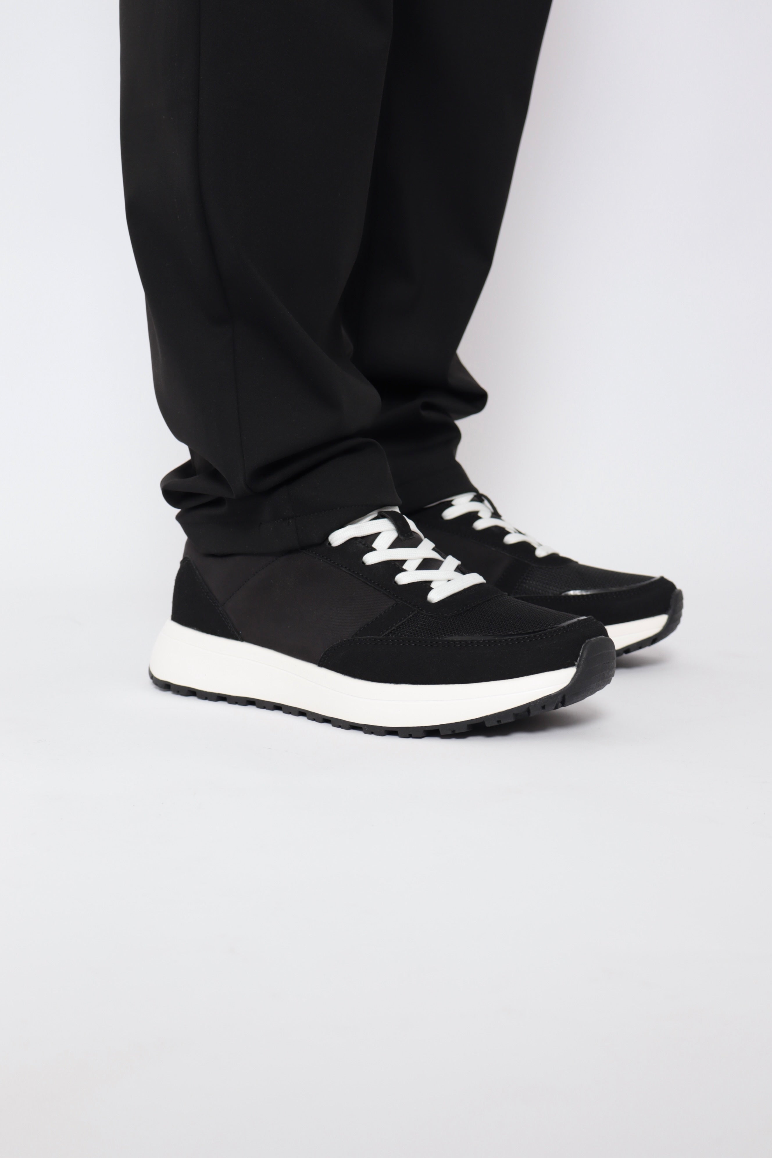 Baskets noires NO LIMIT pour la ville, en toile avec lacets blancs, vue de face sur une surface en bois.